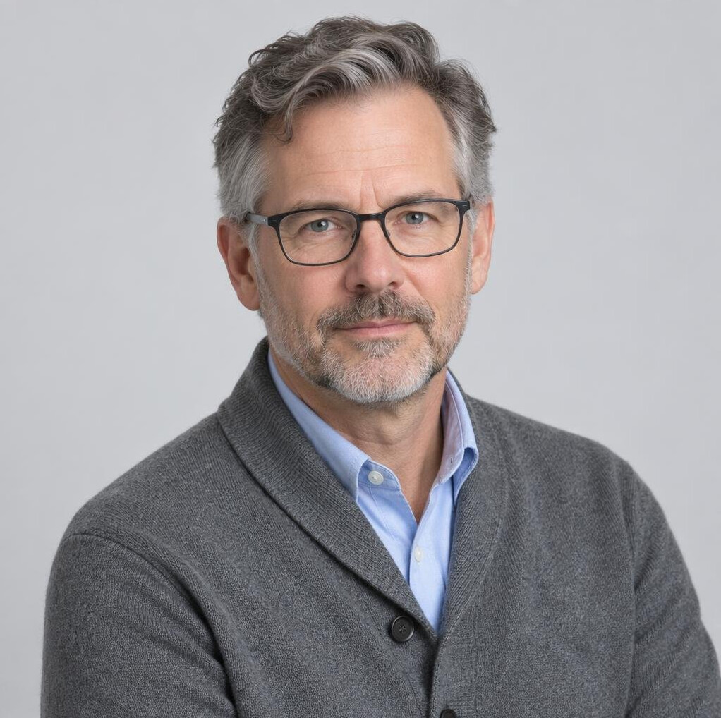 Studio portrait of a white Canadian man editor with glasses